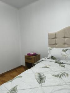 a bed with a white blanket with leaves on it at Hostal jm in Huancayo
