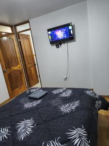 a bedroom with a bed with a tv on the wall at Hostal jm in Huancayo