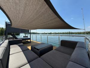 a boat with a couch and seats on the water at Hausboot TraumZeitBoot Jutta - exklusiver Festlieger in perfekter Lage am Scharmützelsee Bad Saarow in Bad Saarow