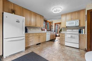 a kitchen with white appliances and wooden cabinets at Grammy's Famous Lake House Retreat in East Hampton