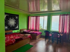 a green bedroom with two beds and a table and chairs at Hotel Chandra Paradise in Munsyari +4 photos