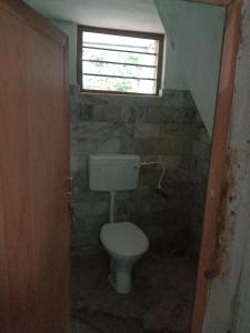 a small bathroom with a toilet and a window at Kailas in Kollam