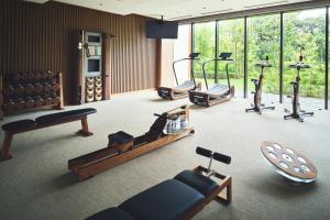 a gym with several exercise equipment in a room with windows at Hotel Indigo Inuyama Urakuen Garden by IHG in Inuyama