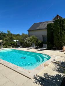 a swimming pool with two chairs and a house at ECOLE DE MATHUNA Chambre d hotes familiale sejour calme avec piscine et jardin in Marigny-Brizay