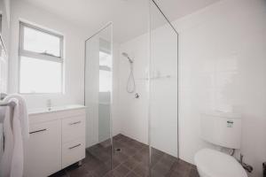 a white bathroom with a shower and a toilet at Ruby SoHo Spa Villa in Port Sorell +36 photos
