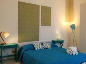 ein Schlafzimmer mit einem blauen Bett und zwei grünen Tischen in der Unterkunft Le Luminarie - Creative Residence in Balestrate