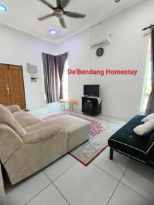 a living room with a couch and a sign on the wall at De'Bendang Homestay Pendang in Pendang