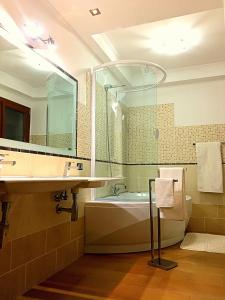 uma casa de banho com uma banheira, um lavatório e um espelho. em B&B Didova em Gavoi
