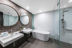 a bathroom with two sinks and a mirror at Vibe Hotel Canberra in Canberra +21 photos