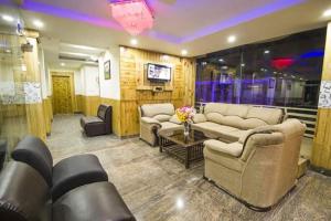 a living room with couches and a table and a tv at Marina Group of hotel Naddi mountain view -cricket stadium 9 km-Mcleodganj 2 km- Bhagsunag 4 in Dharamshala