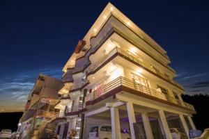 a tall white building with a balcony at night at Mountain Mount view # triund track 2 km#Free Parking-cricket stadium 8 km-Mcleodganj 2 km in Dharamshala