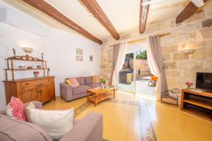 a living room with a couch and a tv at Il-Mohba Holiday Home in Munxar