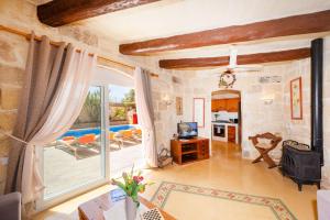 a living room with a large window and a television at Il-Mohba Holiday Home in Munxar +15 photos