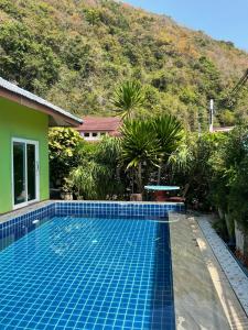 a swimming pool in front of a house with a mountain at Khwaeng Phao Beech Poolvilla in Ban Thung Khanan