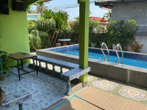 a pool with a bench and a table next to a building at Khwaeng Phao Beech Poolvilla in Ban Thung Khanan