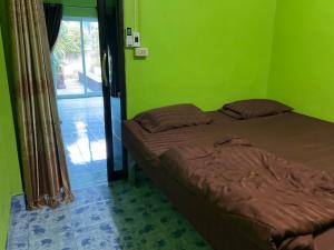 a bed in a room with a green wall at Khwaeng Phao Beech Poolvilla in Ban Thung Khanan