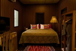 a bedroom with a bed and a lamp and a television at Baan Phraya Suren บ้านพระยาสุเรนทร์ in Ban Thab Mak
