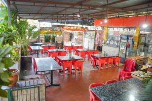 an empty restaurant with tables and red chairs at Hotel Sai Mahima, Near Sai Baba Temple in Shirdi