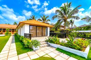 a house with a garden and palm trees at Resort Terra Paraiso Goa - A Beach Property in Calangute