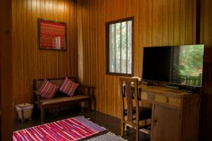 a living room with a flat screen tv and a chair at Baan Phraya Suren บ้านพระยาสุเรนทร์ in Ban Thab Mak
