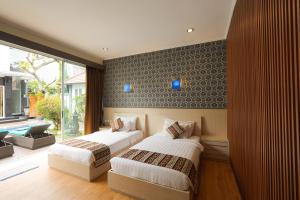 a bedroom with two beds and a window at The Nakula Villas in Legian +65 photos