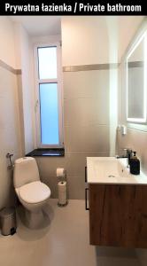a bathroom with a toilet and a sink and a window at Stacja Jeżyce Pokój #B in Poznań