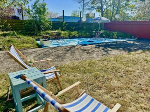 two lawn chairs and an umbrella in a yard at Groland Bornholm B&B in Pedersker