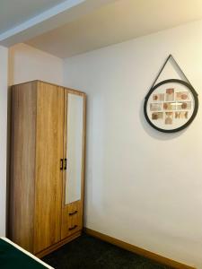 a clock on a wall next to a wooden cabinet at Stacja Jeżyce Pokój #B in Poznań +2 photos