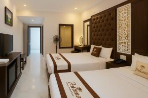 a hotel room with two beds and a flat screen tv at Paloma Hotel Quan Lan in Quan Lạn