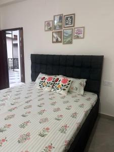 a bed with a black headboard and pillows on it at Cloud & Calm Homestay in Dharmsāla