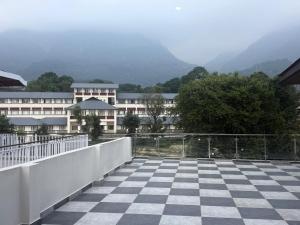 a balcony with a checkered floor in front of a building at Cloud & Calm Homestay in Dharmsāla