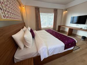 a bedroom with a bed and a desk and a television at The Pham Inn in Bomdila +11 photos