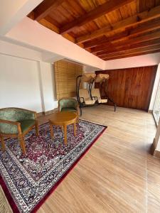a room with two chairs and a table and a rug at The Pham Inn in Bomdila