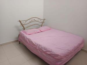 a bed with a pink comforter in a room at Aisyhome in Jitra