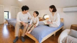 a family sitting on beds in a room at Hostel FIVE ホステルファイブ in Kochi