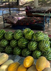 a pile of green and yellow watermelons and a bed at KHAN Hotel in Kokand