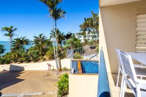 a balcony with a view of the beach and palm trees at Eight, Villa Mar Colina in Yeppoon