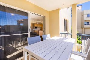 a balcony with a white table and chairs on a patio at Eight, Villa Mar Colina in Yeppoon