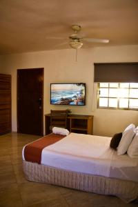 a bedroom with a large bed with a tv on the wall at Hotel Scarlette in Tulum