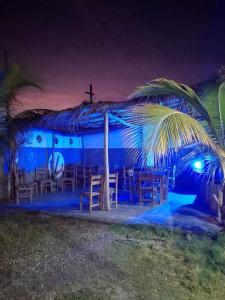 a blue building with a church with a cross and a palm tree at POSADA VSTIKIBAR & RESTAURANt in Rincón del Pirata