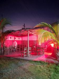 a pink building with tables and chairs and a church at POSADA VSTIKIBAR & RESTAURANt in Rincón del Pirata +11 photos