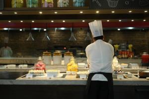 a chef standing in a kitchen preparing food at Courtyard by Marriott Gurugram Downtown in Gurgaon