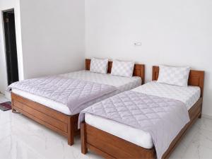 two beds sitting next to each other in a bedroom at Tanjung Inn in Wonosari