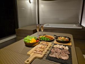 a table with two glasses of wine and meat and vegetables at Villa YUKUI in Onna