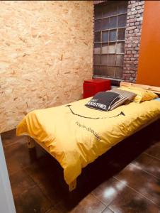 a bed with a yellow comforter in a room at La Mariefacture - Comme au Garage in Laning