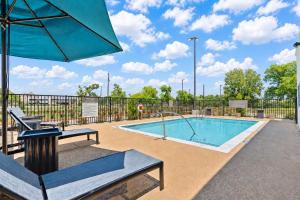 a swimming pool with an umbrella and a table and chairs at Hampton Inn By Hilton Wharton in Wharton