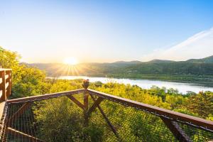 a view of a river from a balcony with the sun setting at Sherpa Pihenőház in Nagymaros