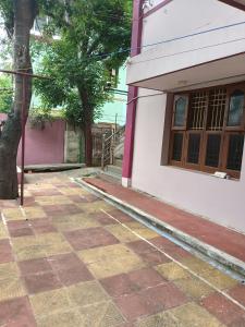 a building with a tree next to a sidewalk at Aiswarya illam in Chidambaram
