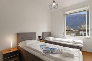 two beds in a bedroom with a window at Bellinzona Center in Bellinzona