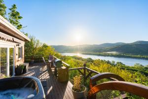 a deck with a hot tub and a view of a river at Sherpa Pihenőház in Nagymaros